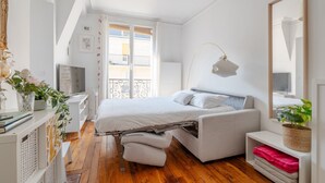 A modern bedroom with a bed, bedside table, and a large window. - Authentic Paris Living – Steps from Montmartre (Paris)