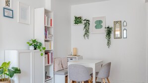 A room with a white desk, two grey chairs, a white bookshelf, and a small side table with a lamp. - Authentic Paris Living – Steps from Montmartre (Paris)