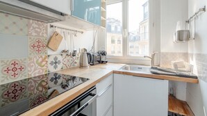A compact kitchen with a window, a kettle, and a toaster. - Authentic Paris Living – Steps from Montmartre (Paris)