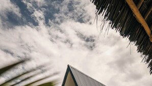 Ett modernt hus med ett triangulärt tak, ett stort fönster och en trädgård med stenar och växter.