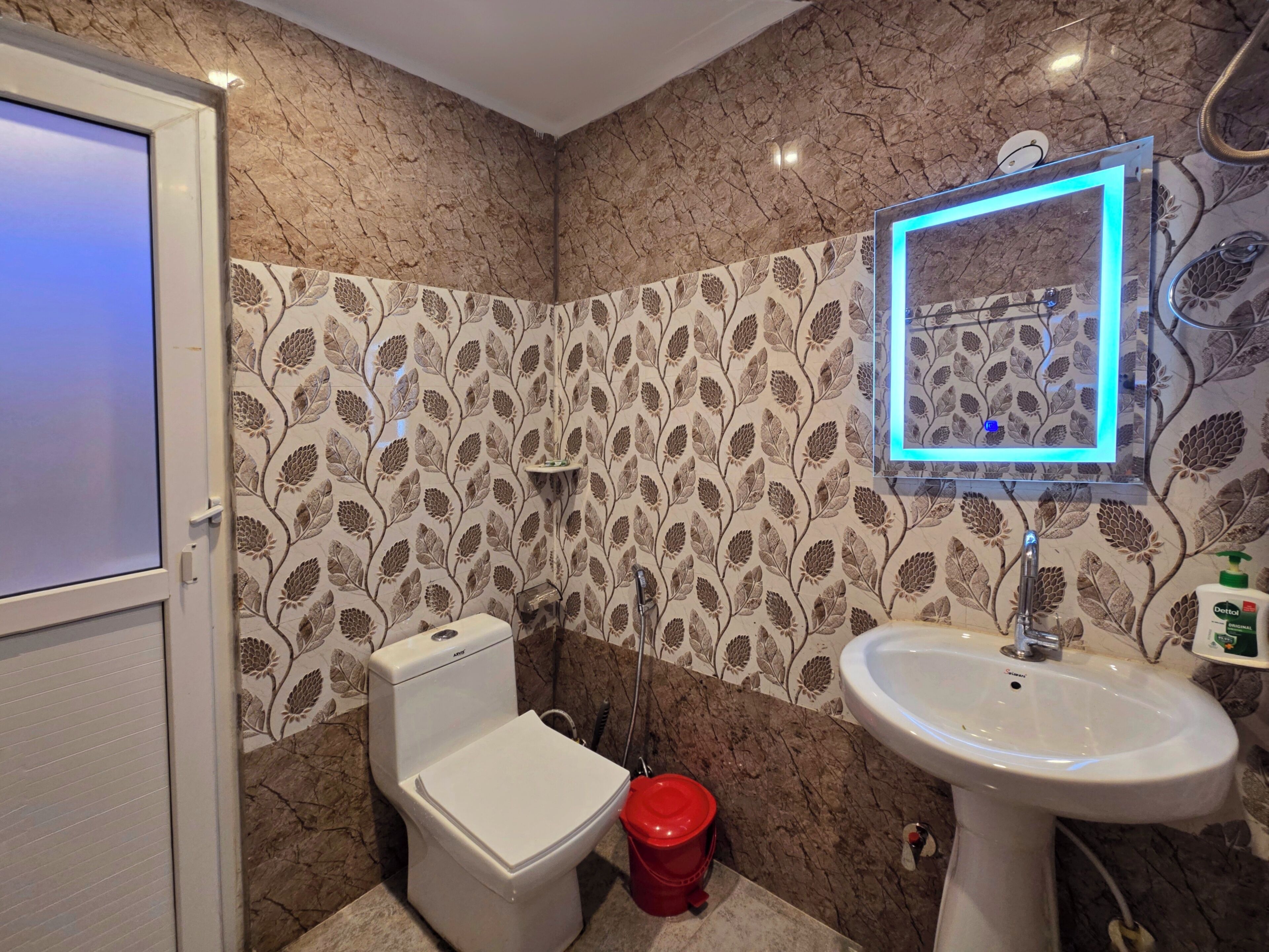 A bathroom with a toilet, sink, and decorative wall tiles.