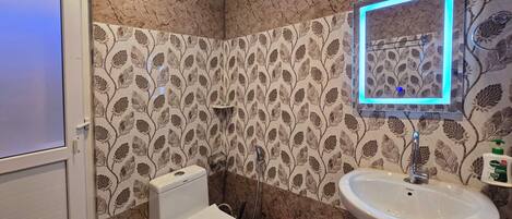 A bathroom with a toilet, sink, and decorative wall tiles.