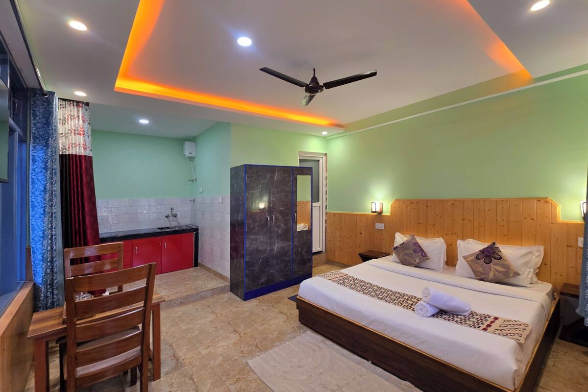 A hotel room with a bed, wooden headboard, a small desk, and a chair.