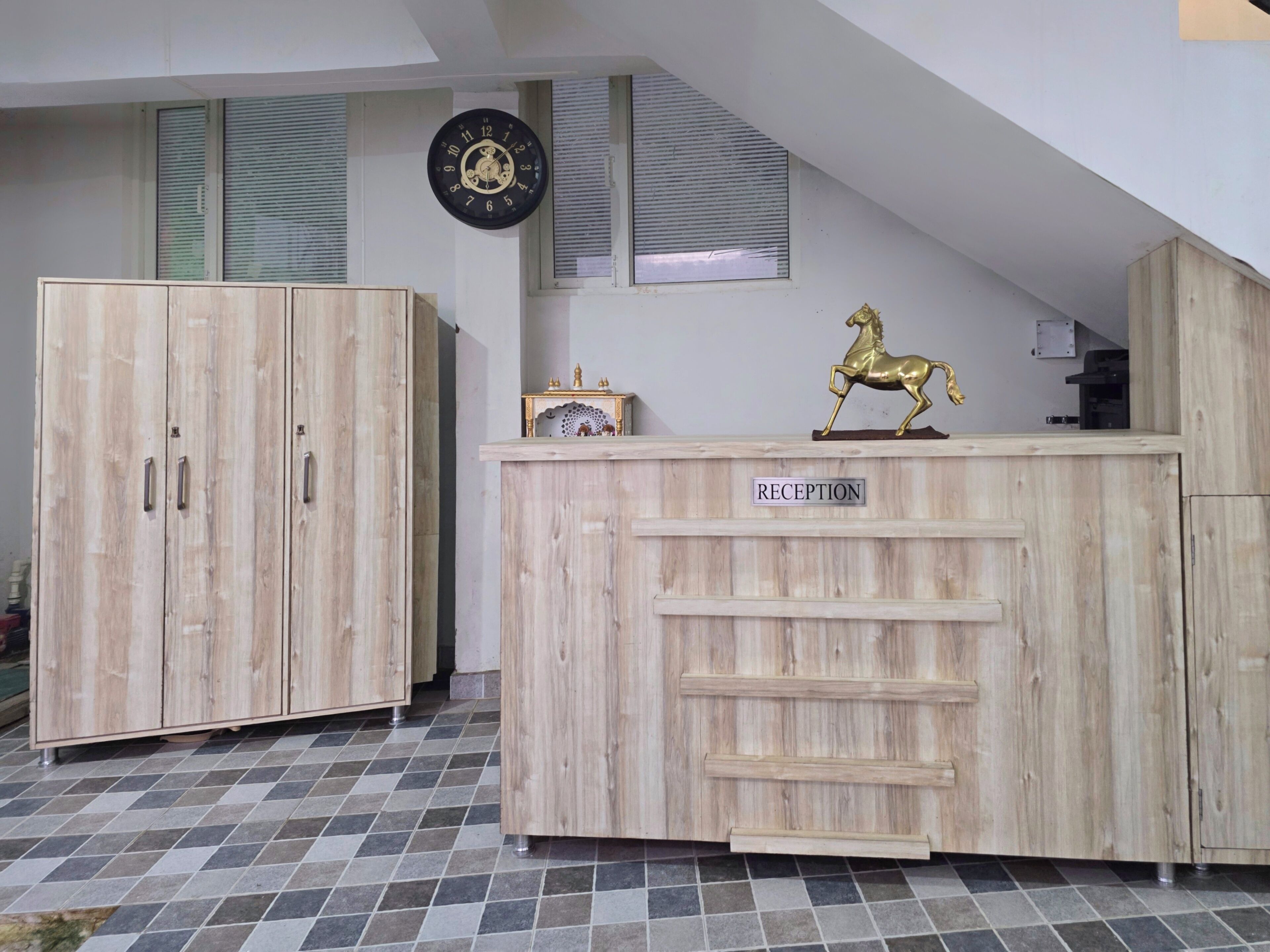 Una recepción con un letrero que dice 'RECEPTION', un armario de madera, un reloj de pared y una estatua dorada de un caballo.