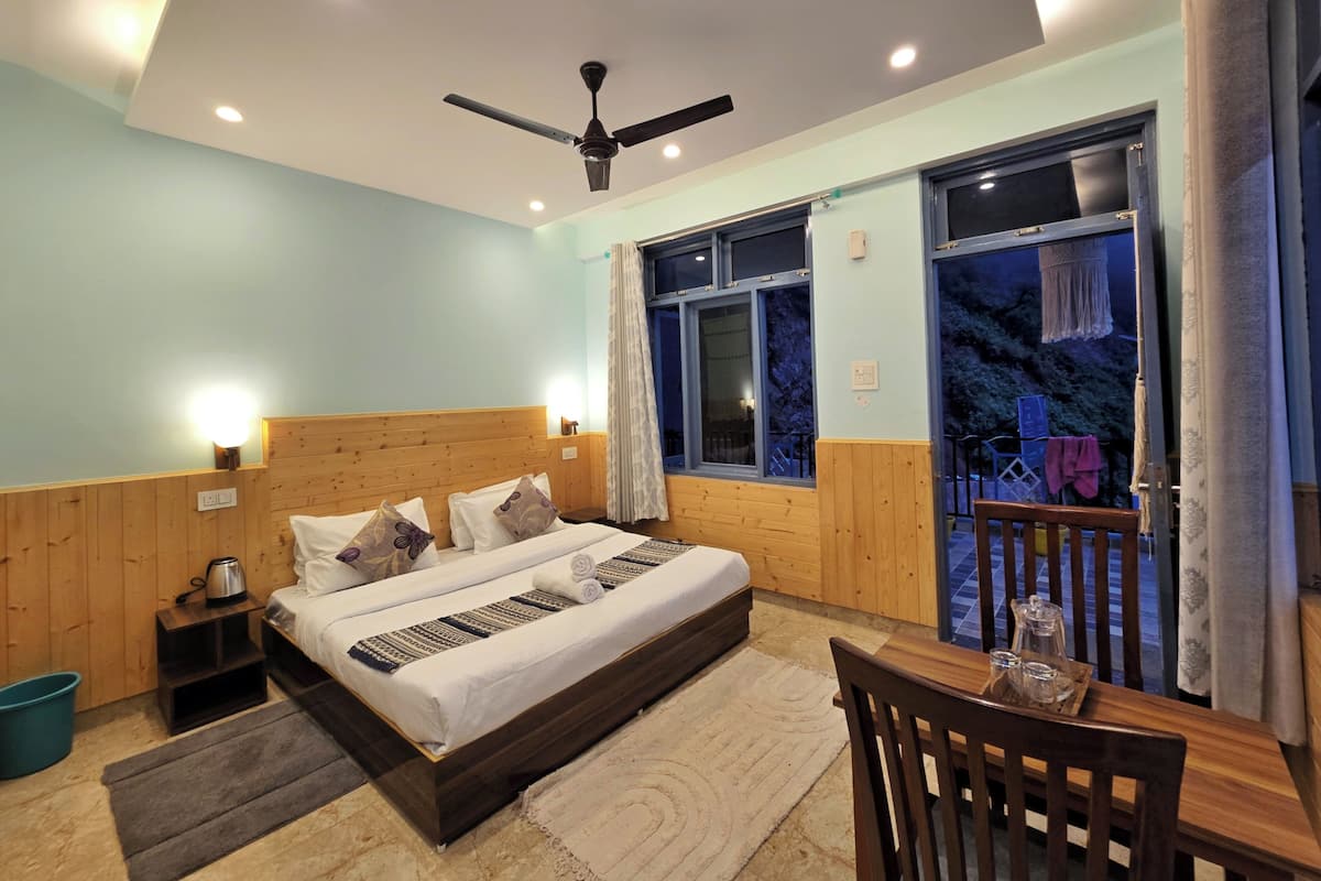 A bedroom with a large bed, wooden headboard, a ceiling fan, and a view of a balcony with a railing.