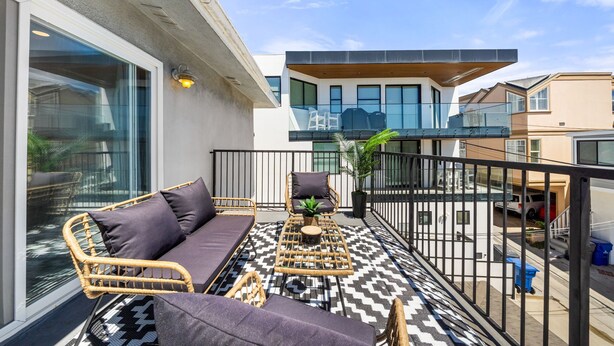 A balcony with wicker furniture, a patterned floor, and a view of a modern building.