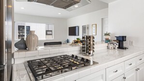 A modern kitchen with white cabinetry, a stainless steel stove, and a built-in range hood.