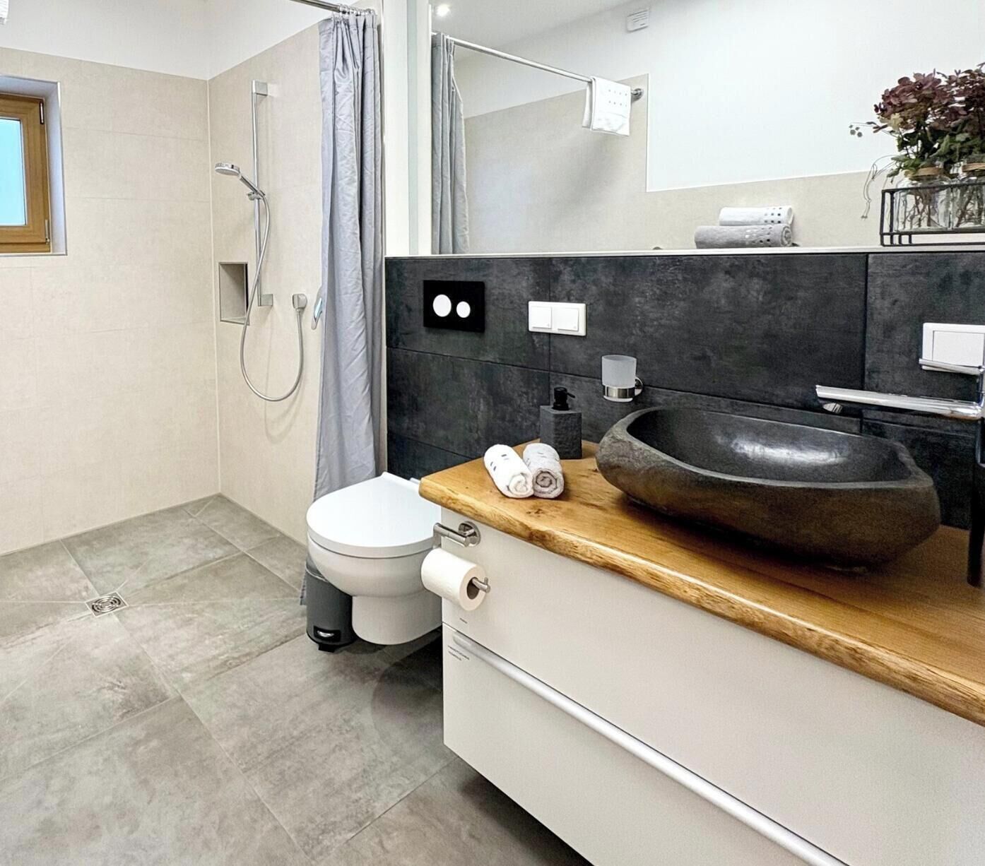 Une salle de bain moderne équipée de toilettes, d’un bidet et d’un grand lavabo sur un plan de toilette en bois.