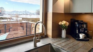 A modern kitchen with a large window, a coffee machine, and a vase with flowers. - Vacation apartment with 3 sep. Bedrooms and bathrooms (Nußdorf i. Chiemgau)