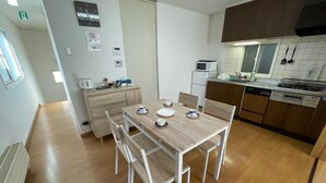 A compact kitchen with a dining table, chairs, a microwave, a refrigerator, and a stove.