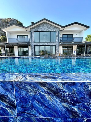 Une maison moderne à deux étages avec une grande piscine à l’avant.