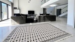 Un vaste espace de vie comprenant un grand canapé, un téléviseur à écran plat et un tapis à motifs.
