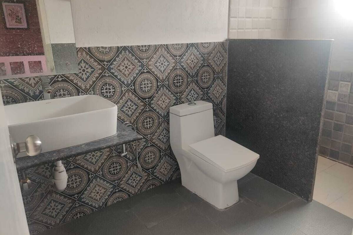 Un baño con salpicadero de azulejos estampados, inodoro blanco y bañera con grifo.