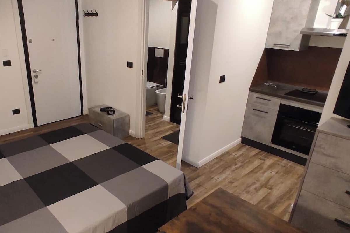 Une pièce de taille modeste comprenant un lit, une petite salle de bain et une kitchenette.