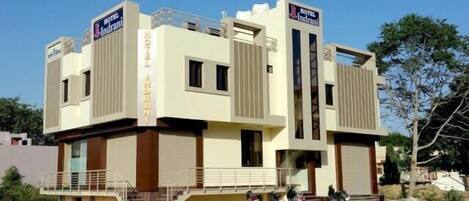 A two-story hotel with a modern design, featuring a flat roof and a central entrance with steps.
