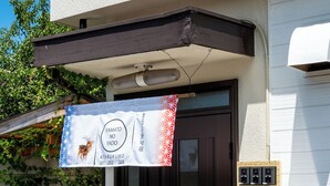 A building entrance with a dark brown door, a banner hanging above, and a mailbox on the right.