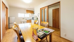 A dining area with a wooden table, chairs, and a kitchen in the background.