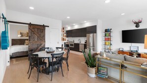 A modern living space with a dining area, kitchen, and a seating area with a TV.