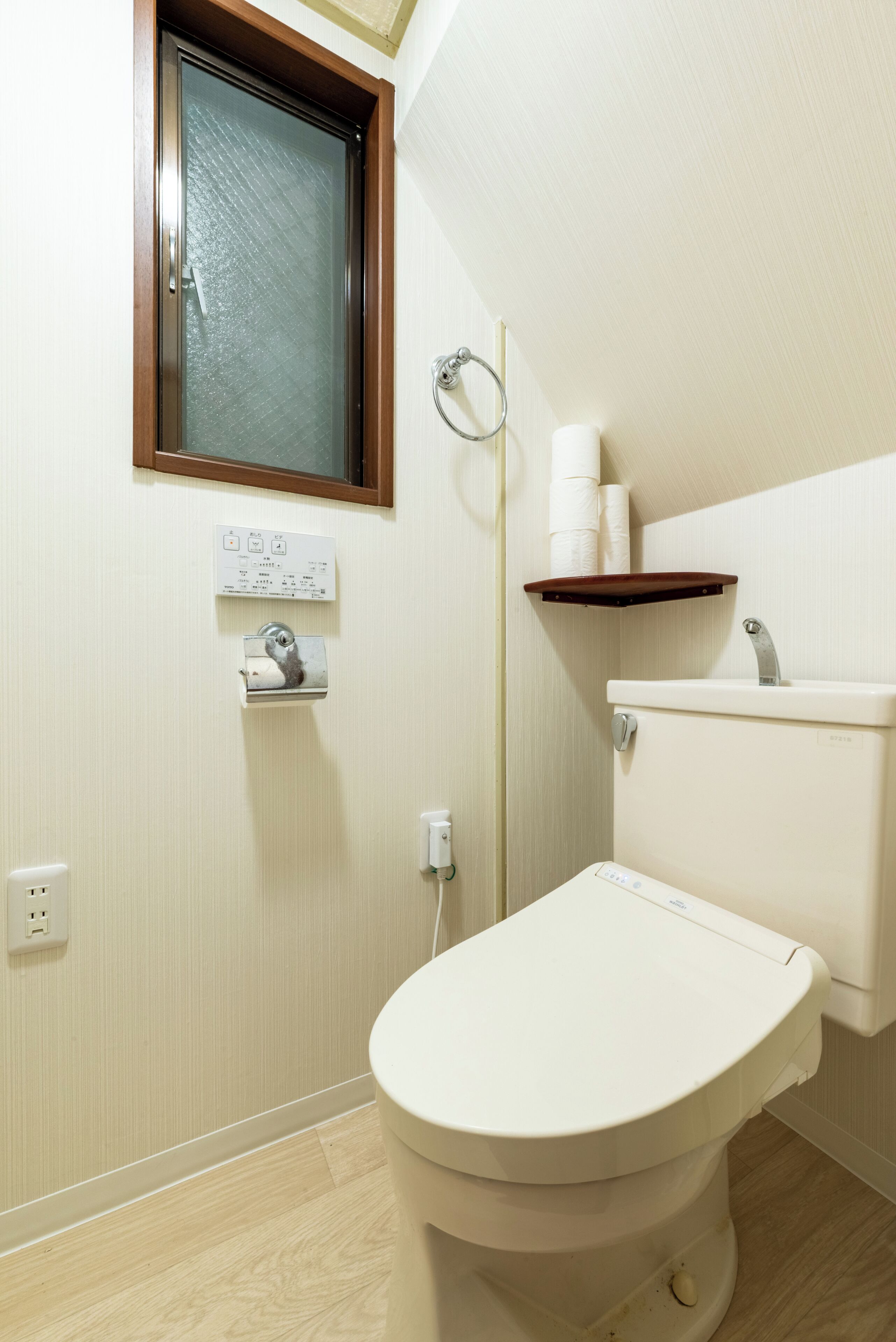 A small, clean bathroom with a toilet, a sink, and a window.