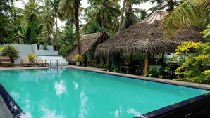 A swimming pool with a thatched roof structure and lounge chairs. - Surf and Zen - Coworking and Coliving Habaraduwa (Habaraduwa)