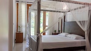 A bedroom with a four-poster bed, a wooden nightstand, and a potted plant. - Surf and Zen - Coworking and Coliving Habaraduwa (Habaraduwa)