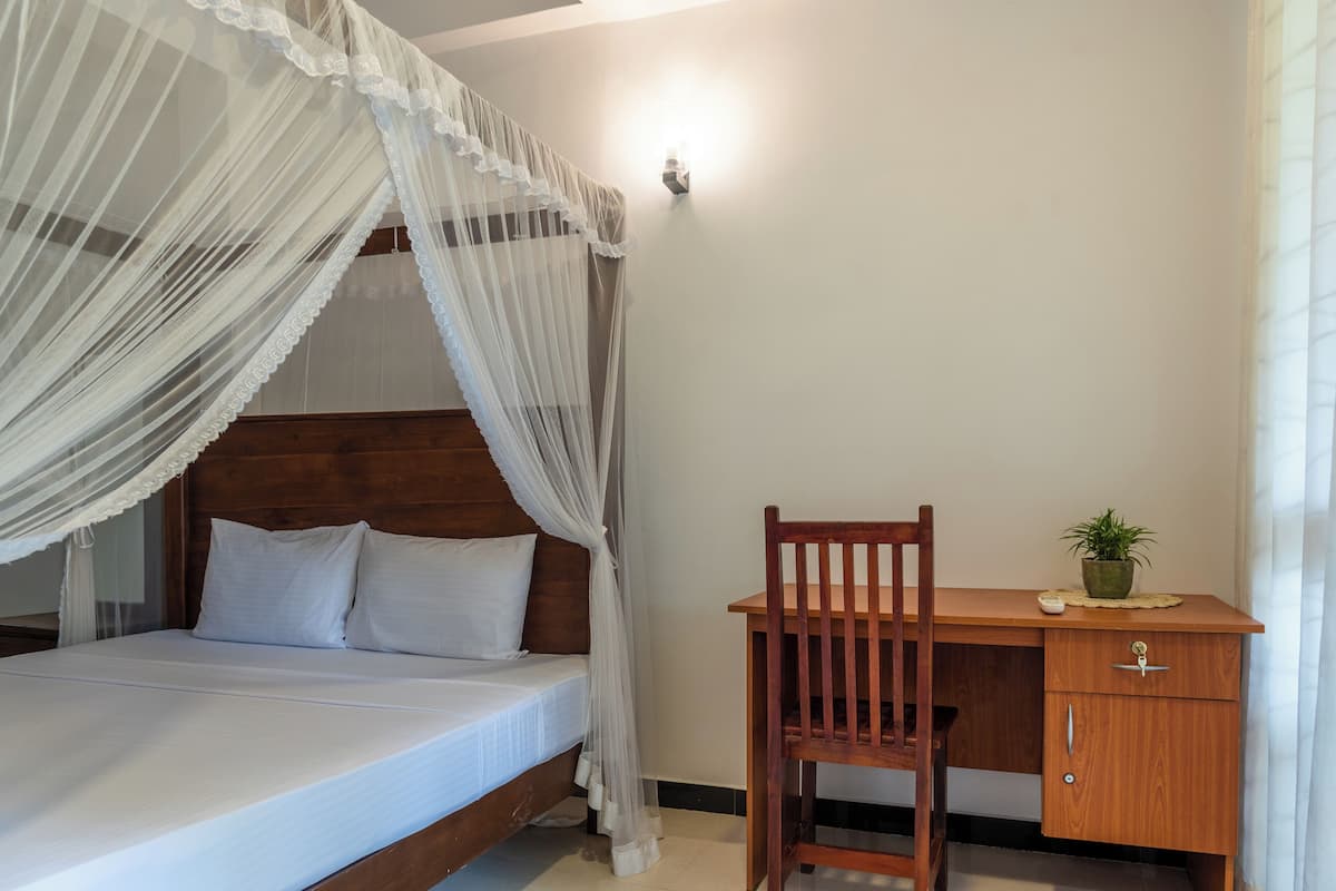 Un dormitorio con una cama de madera, un escritorio con una silla y una lámpara fijada a la pared.