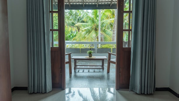 A room with a wooden bench, a potted plant, and a view of lush greenery through a window. - Surf and Zen - Coworking and Coliving Habaraduwa (Habaraduwa)