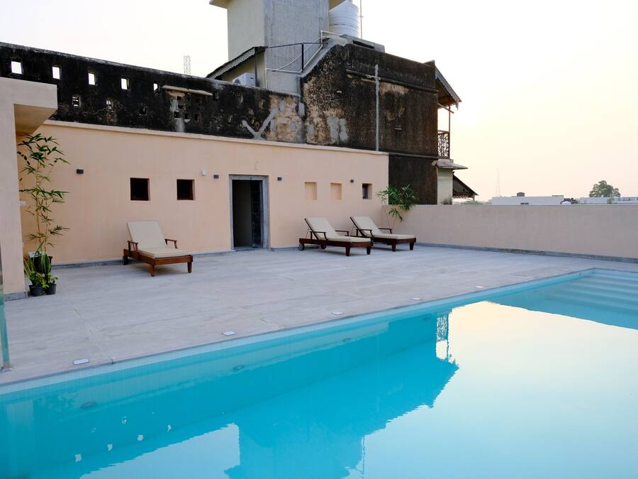 A rooftop pool area with two lounge chairs and a door leading to a building.