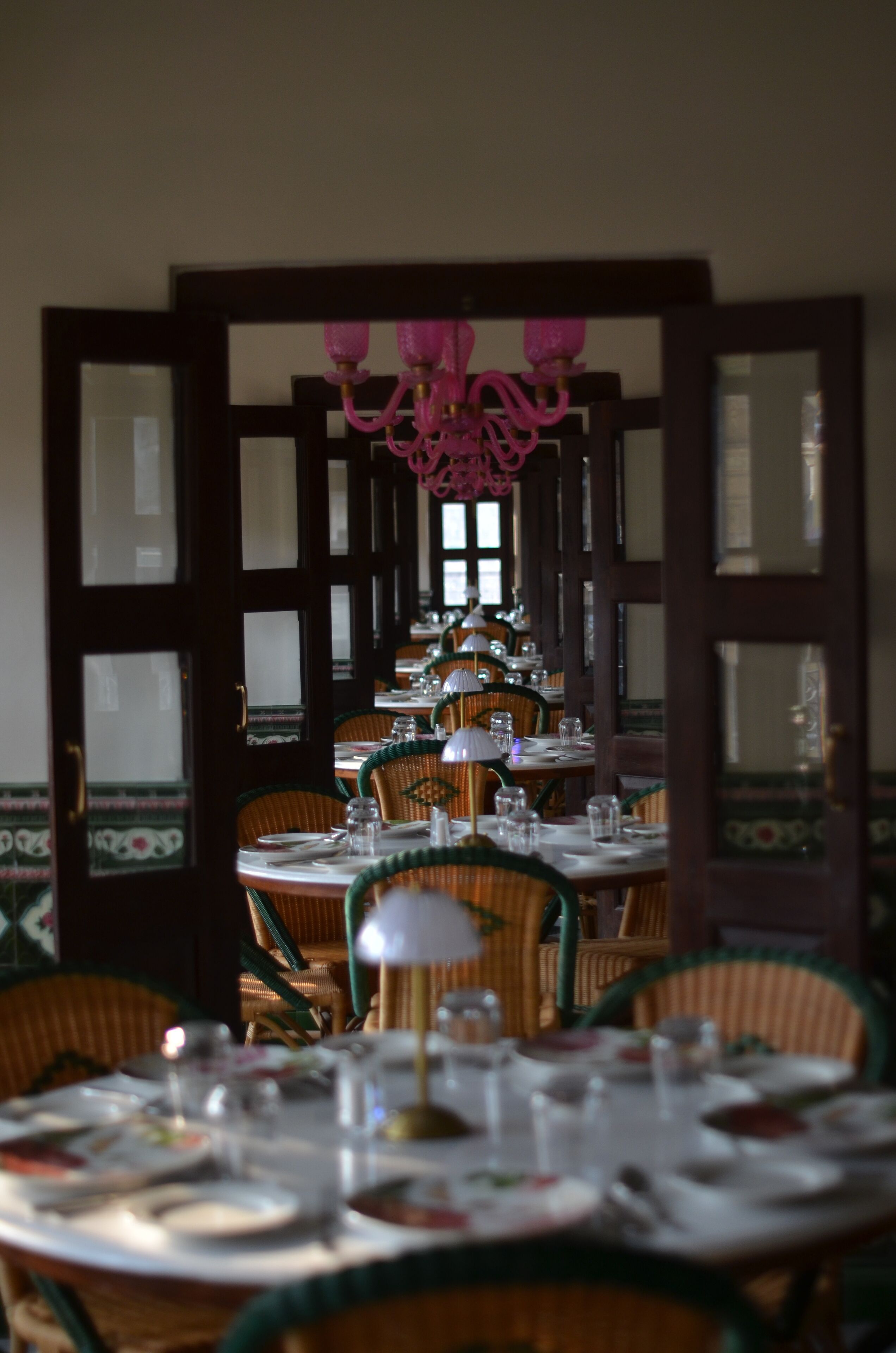 Un comedor con mesas redondas, sillas y un candelabro.