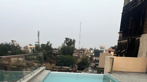 A rooftop swimming pool with a clear view of the surrounding buildings and a flagpole in the background. - Vivaana  Museum Hotel (Nawalgarh)