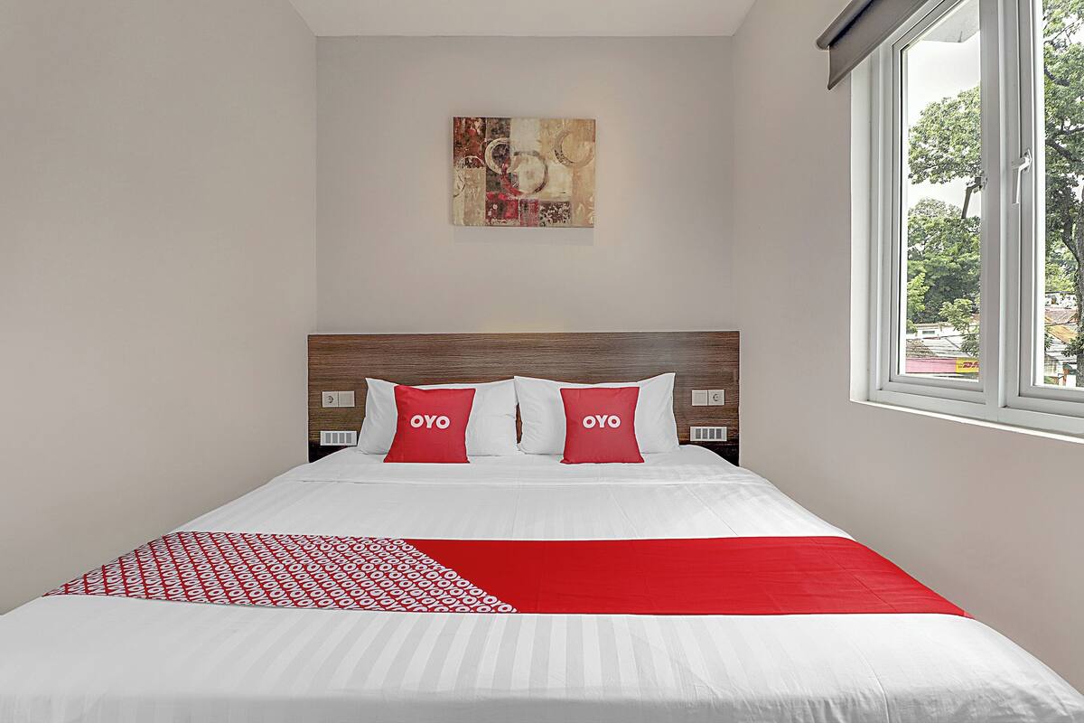 A neatly made bed with a patterned bedspread and two pillows with the word "OYO" on them.