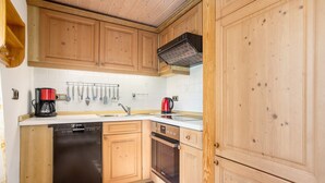 Una cocina con armarios de madera, lavavajillas, horno y cafetera.