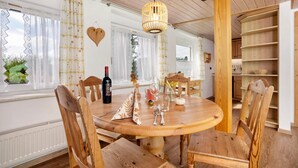 Una mesa de comedor de madera con sillas, una lámpara colgante y una decoración con forma de corazón en la pared.