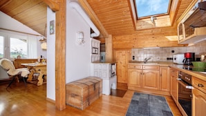 Een houten interieur met een bank, een raam en een keukenhoek.