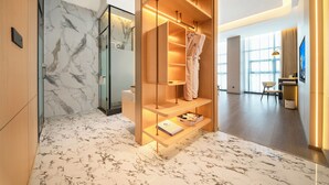 Ein modernes Hotelzimmer mit Marmorboden, Holzschrank und Duschkabine aus Glas.