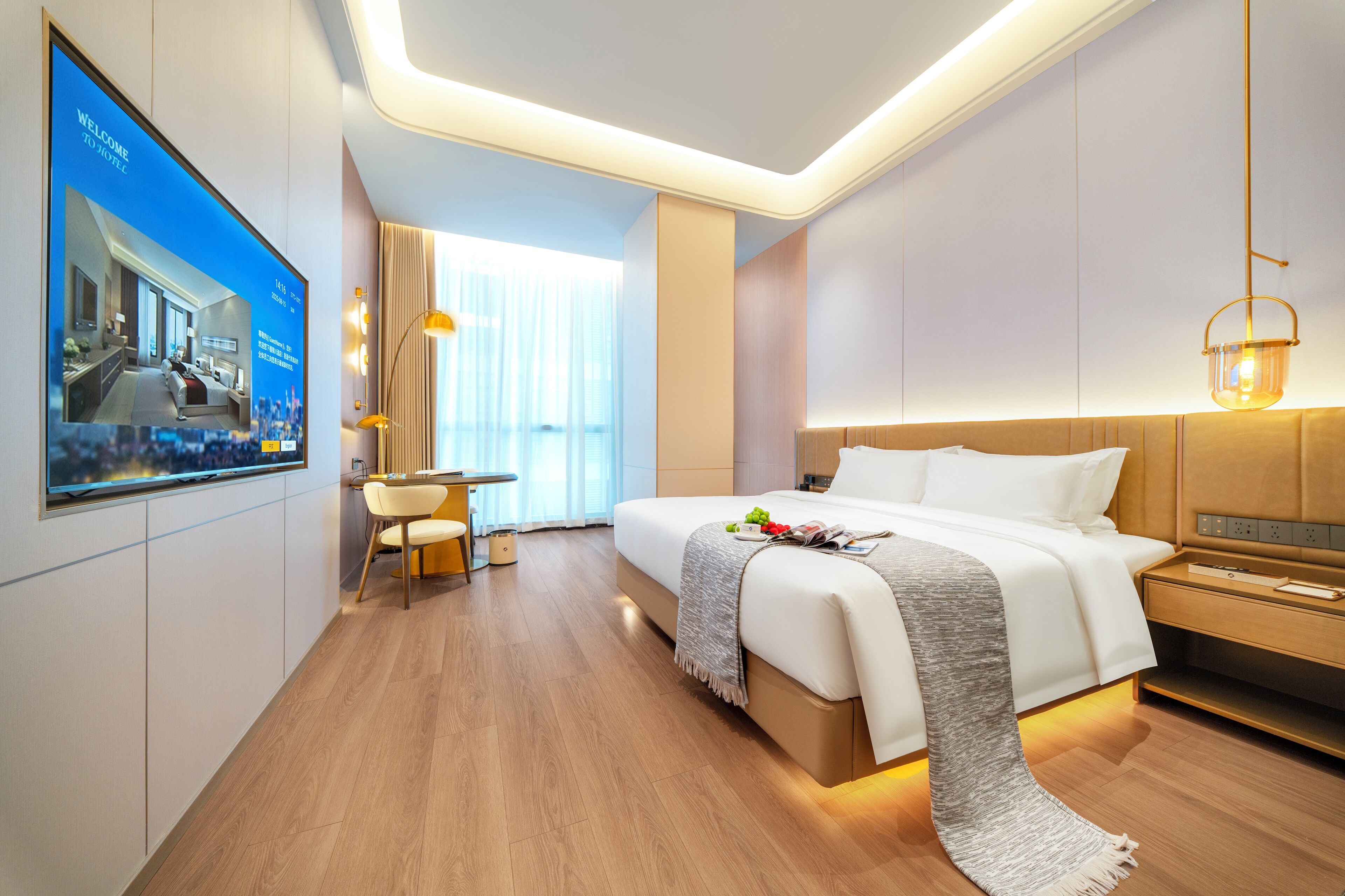 A modern hotel room with a large bed, bedside table, and a TV displaying a welcome message.