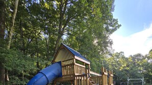 A wooden playground structure with a slide and a climbing ladder.