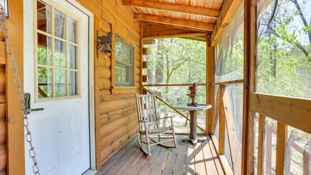 A wooden cabin with a porch, a door with a bell, and a table with chairs.