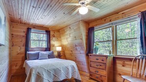 Un dormitorio rústico de cabaña con cama, cómoda y silla.