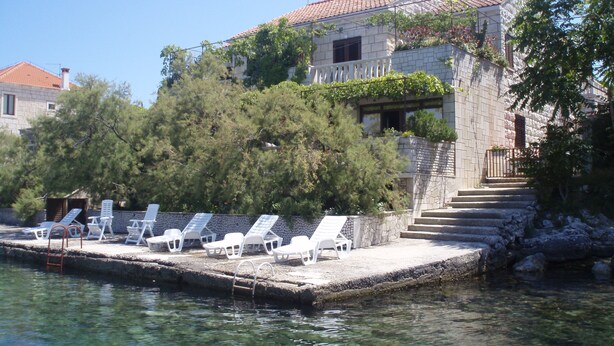 A stone building with a tiled roof, a pool with lounge chairs, and a staircase leading to the building. - Stone House Gregov, Lumbarda 317- Hr (Lumbarda)