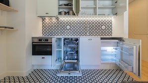 Una cocina compacta con horno integrado, lavavajillas y refrigerador.