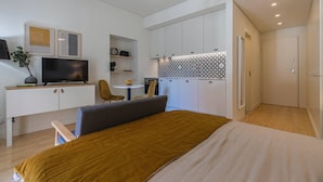 Una habitación de hotel moderna con cama, televisor, escritorio y kitchenette.