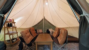 Une tente avec une table en bois et quatre chaises rembourrées disposées autour.
