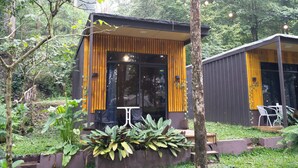Un bâtiment moderne doté de grandes fenêtres et d’une façade en bois, entouré d’une végétation luxuriante.