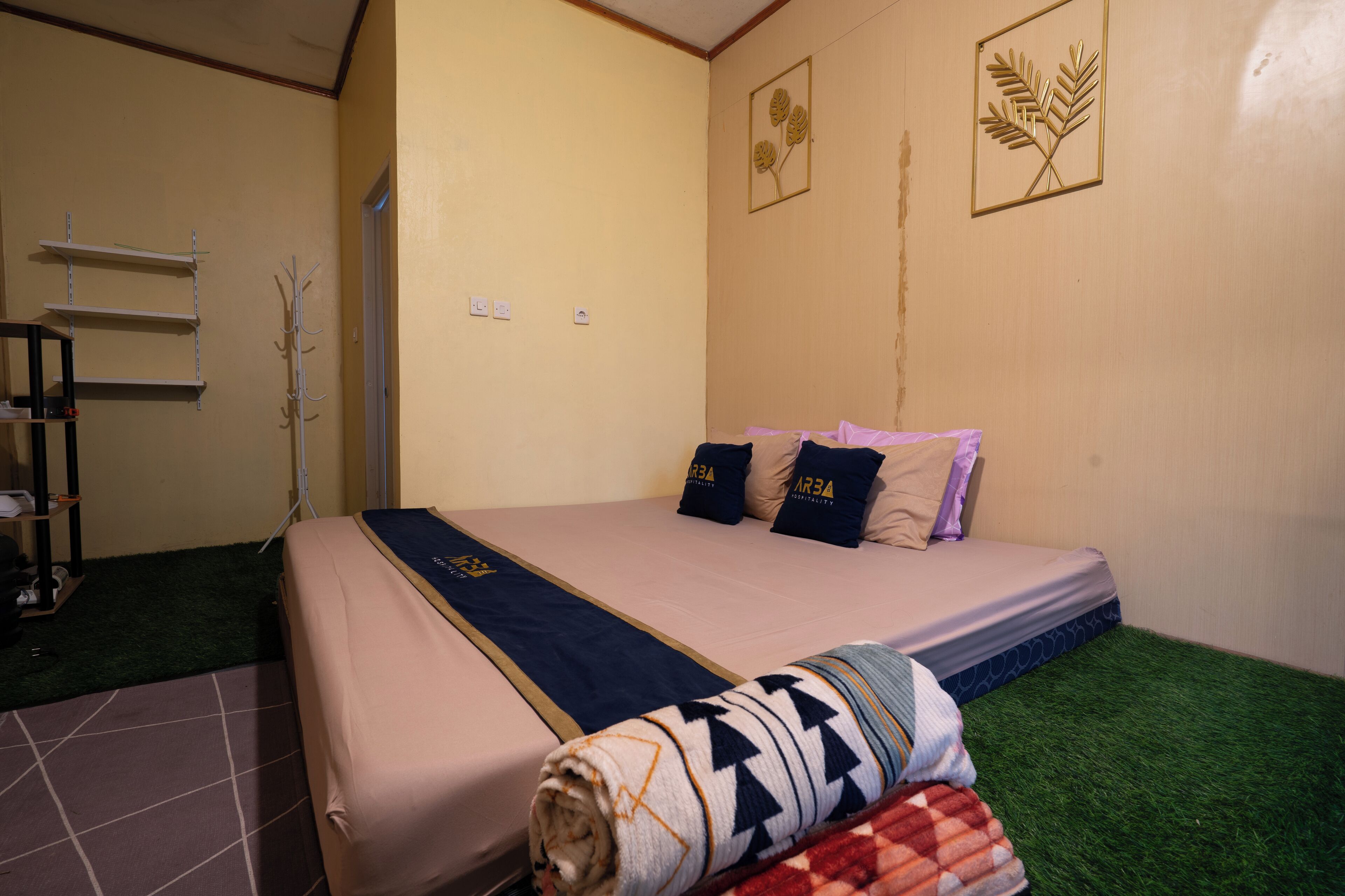Una habitación con cama, perchero y estantería.
