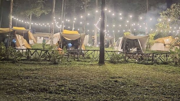 A campsite at night with multiple tents and string lights.