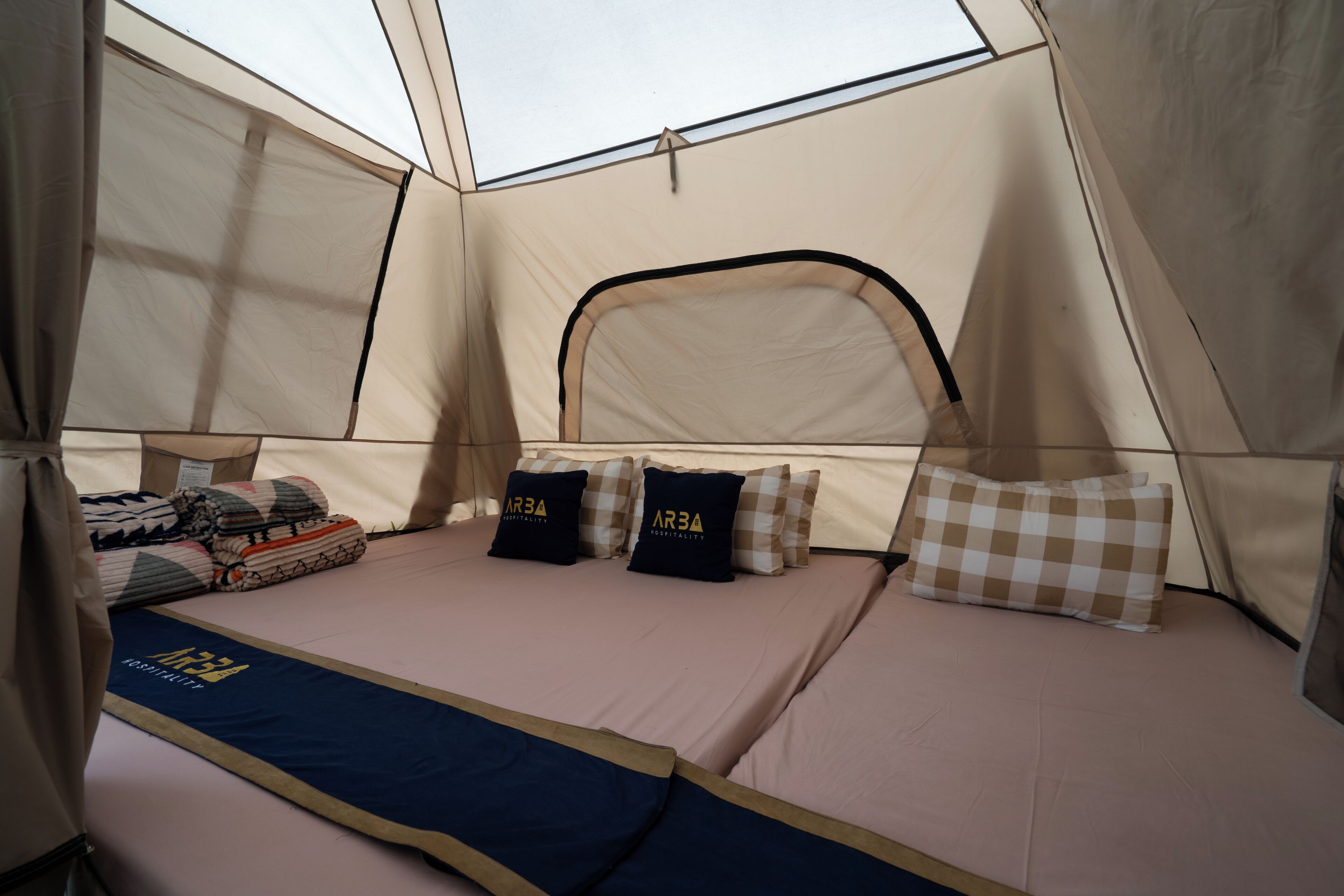 A tented room with a bed, pillows, and a blue mat.