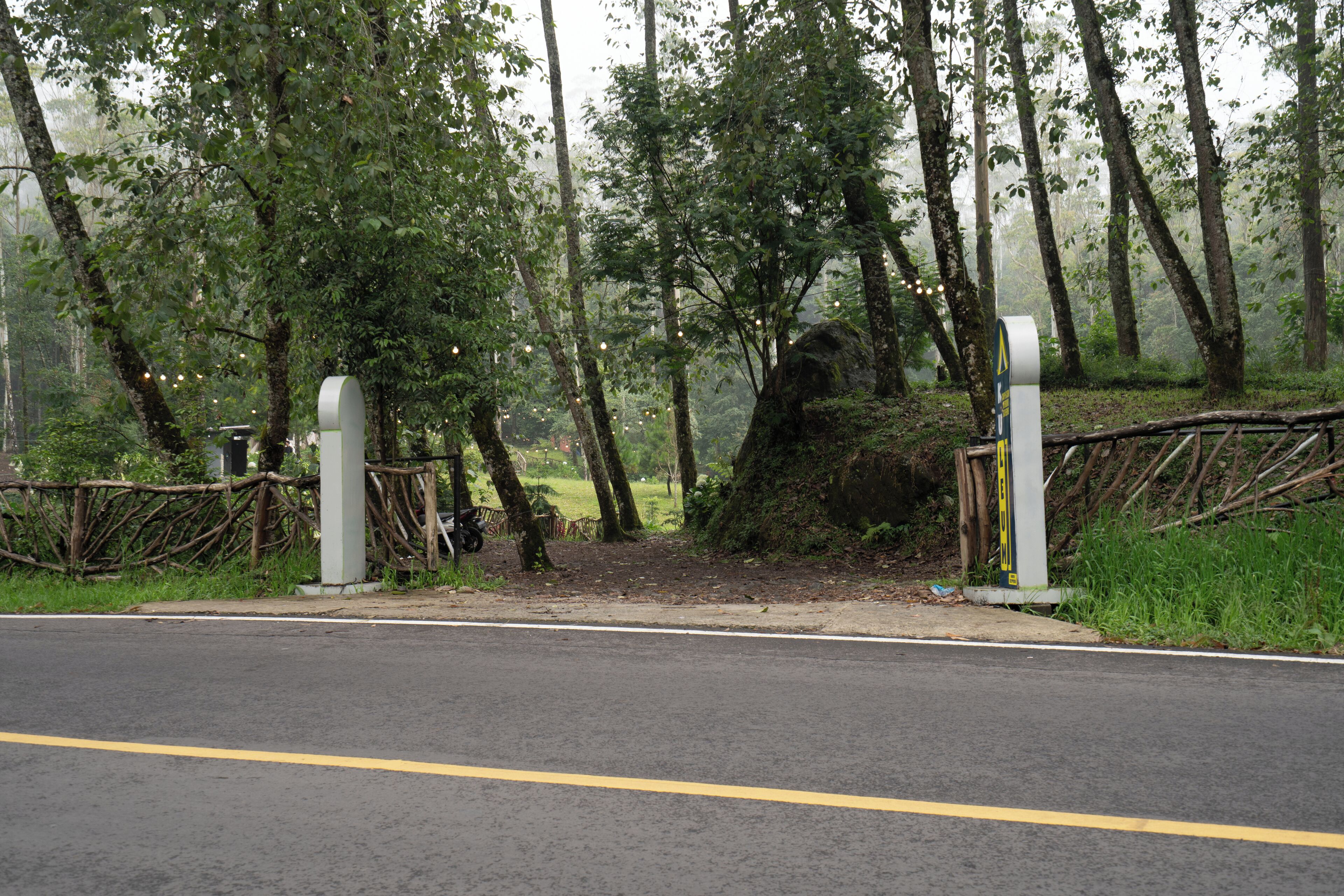 A road with a metal gate and a wooden fence.