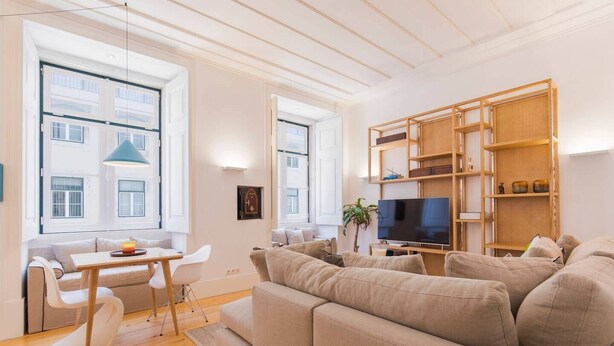 A modern living room with a sofa, a TV, and a wooden bookshelf. - Charming apartment in Baixa Chiado (Lisboa)