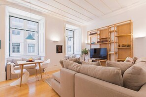 A modern living room with a sofa, a TV, and a wooden bookshelf. - Charming apartment in Baixa Chiado (Lisboa)